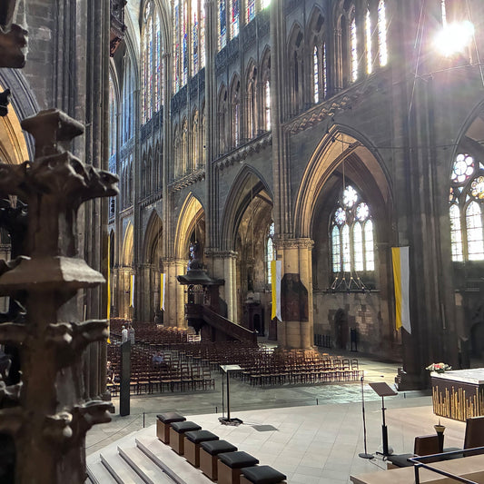 Interior view of Gothic cathedral saint etienne in metz france showing tall pointed arches, ribbed vaulting, and large stained glass windows with wooden chairs arranged in nave